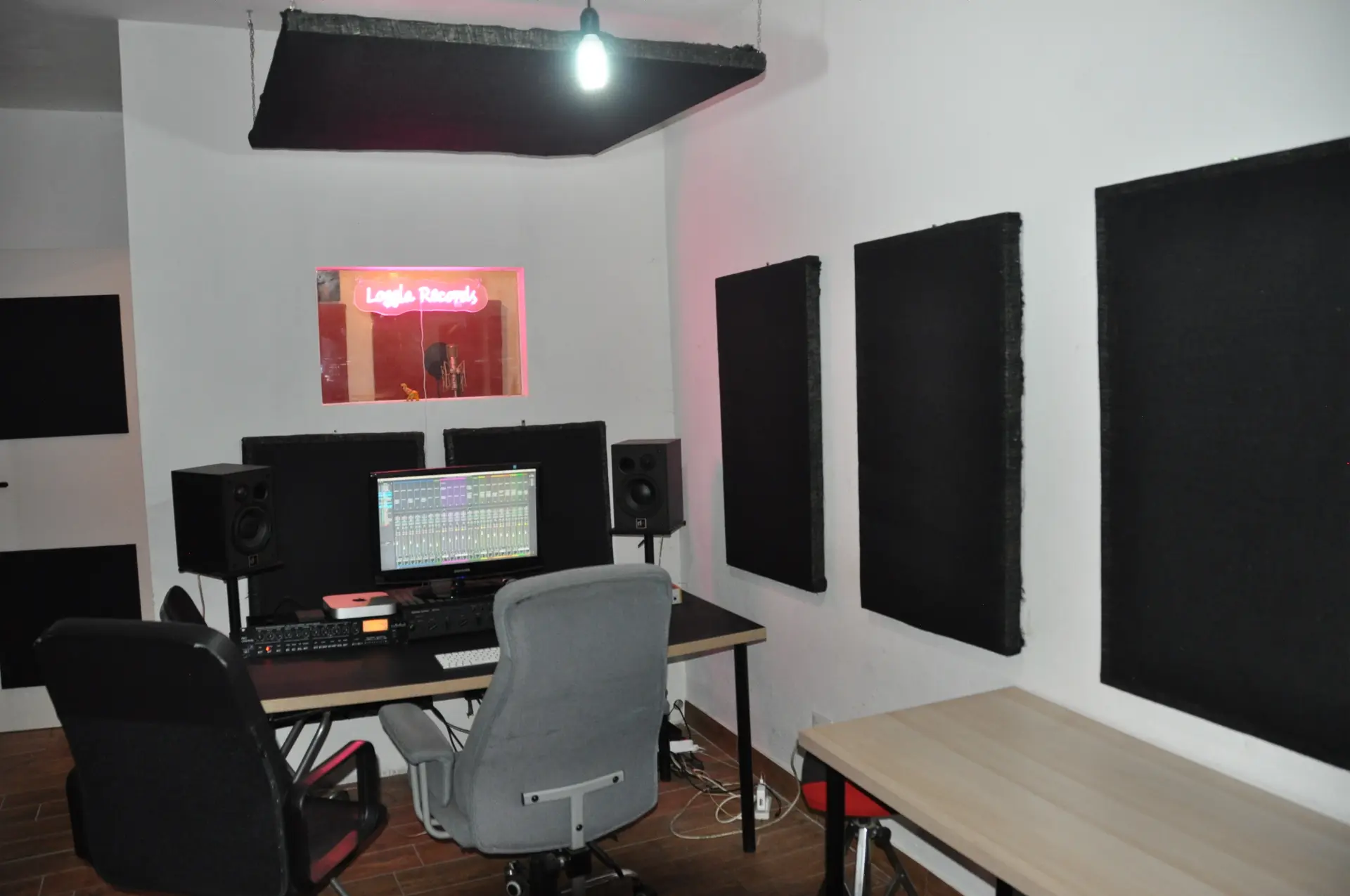 Regia dello studio Loggia Records con monitor e insegna al neon
